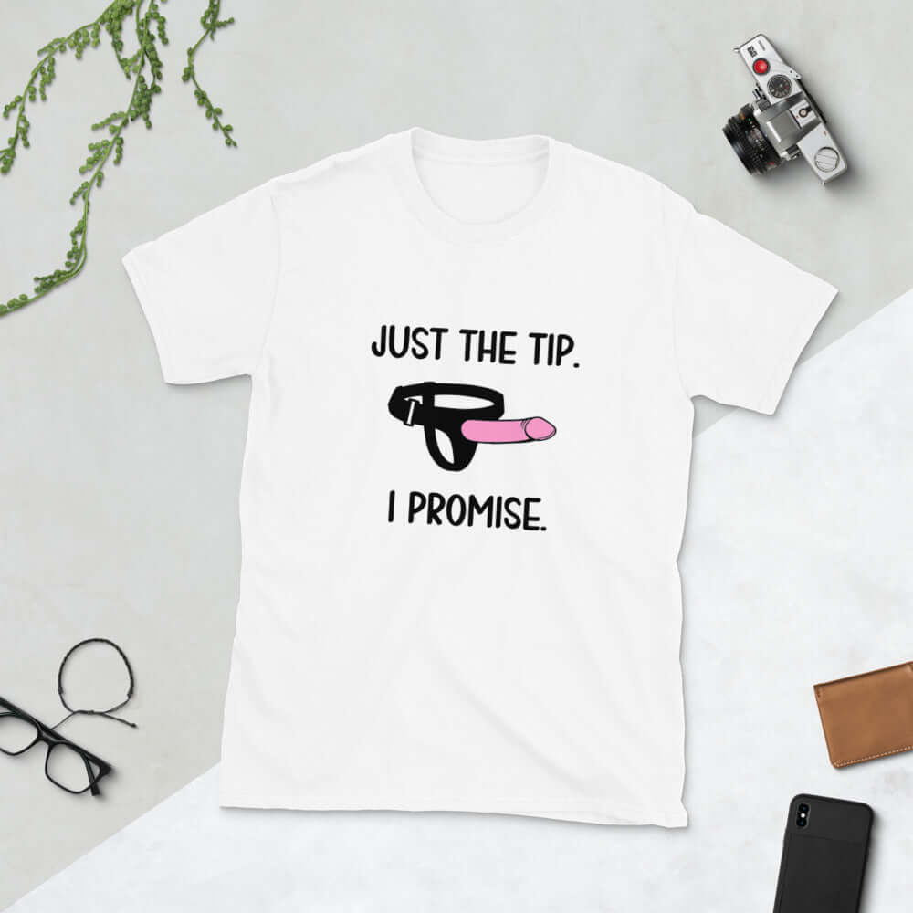 White t-shirt that has an image of a strap-on dildo and the words Just the tip, I promise printed on the front. The graphics are pink, black and white.