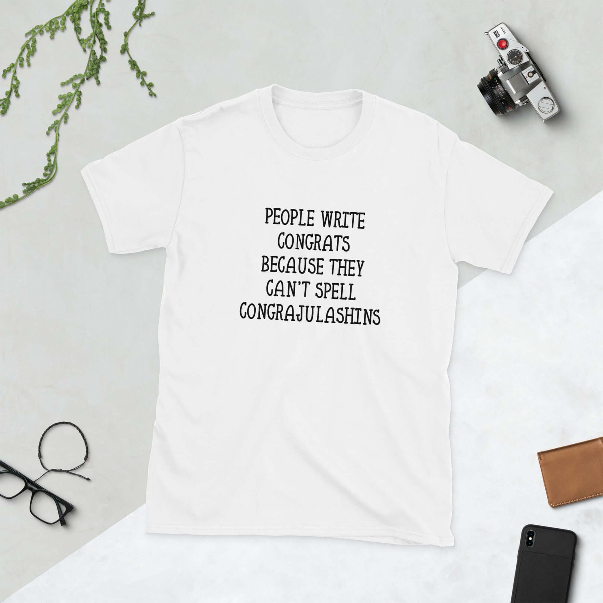 White t-shirt with the words People write congrats because they can't spell congratulations printed on the front. The word congratulations is intentionally misspelled.