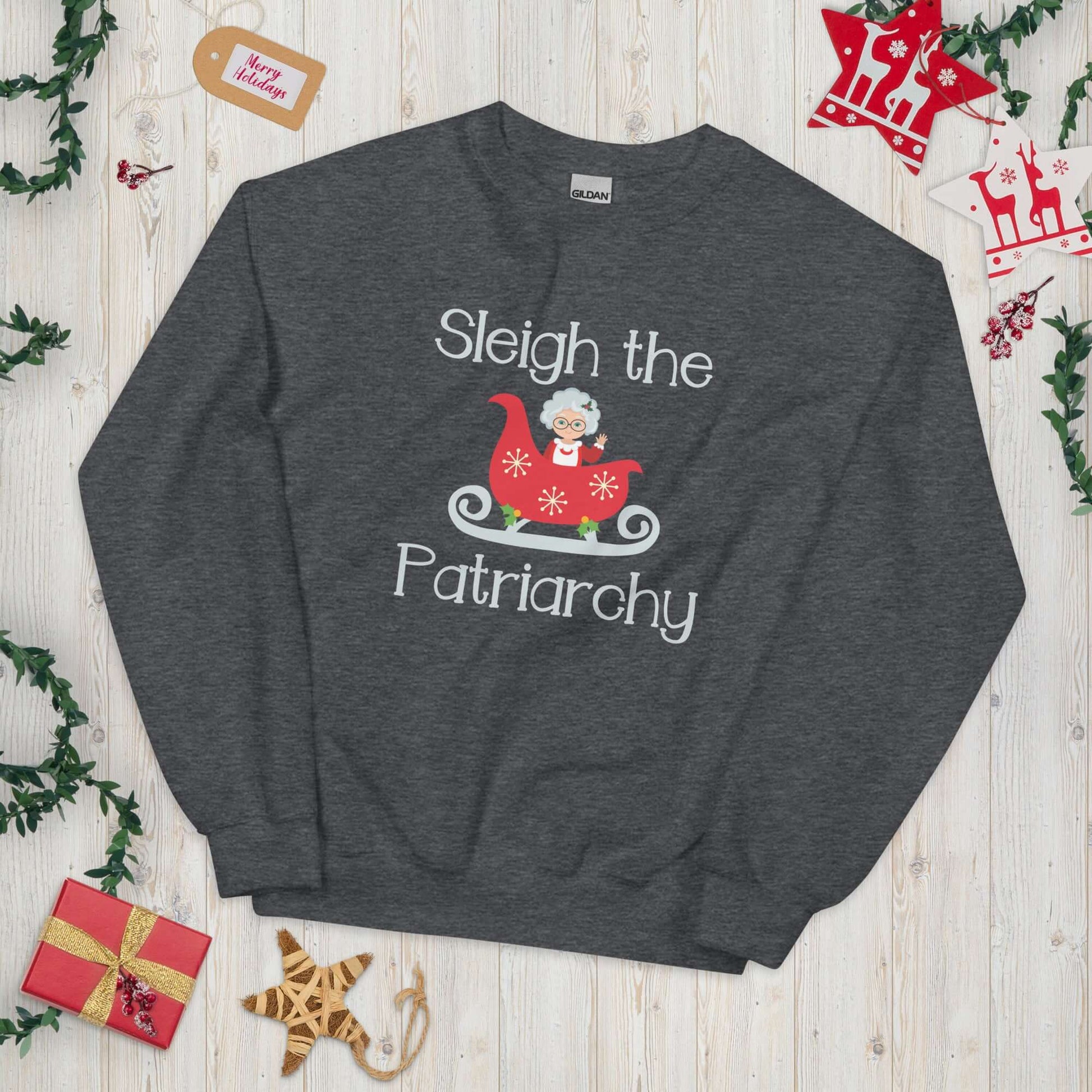 Dark grey crewneck sweatshirt with graphic of Mrs. Claus sitting in a sleigh and the words Sleigh the patriarchy printed on the front.