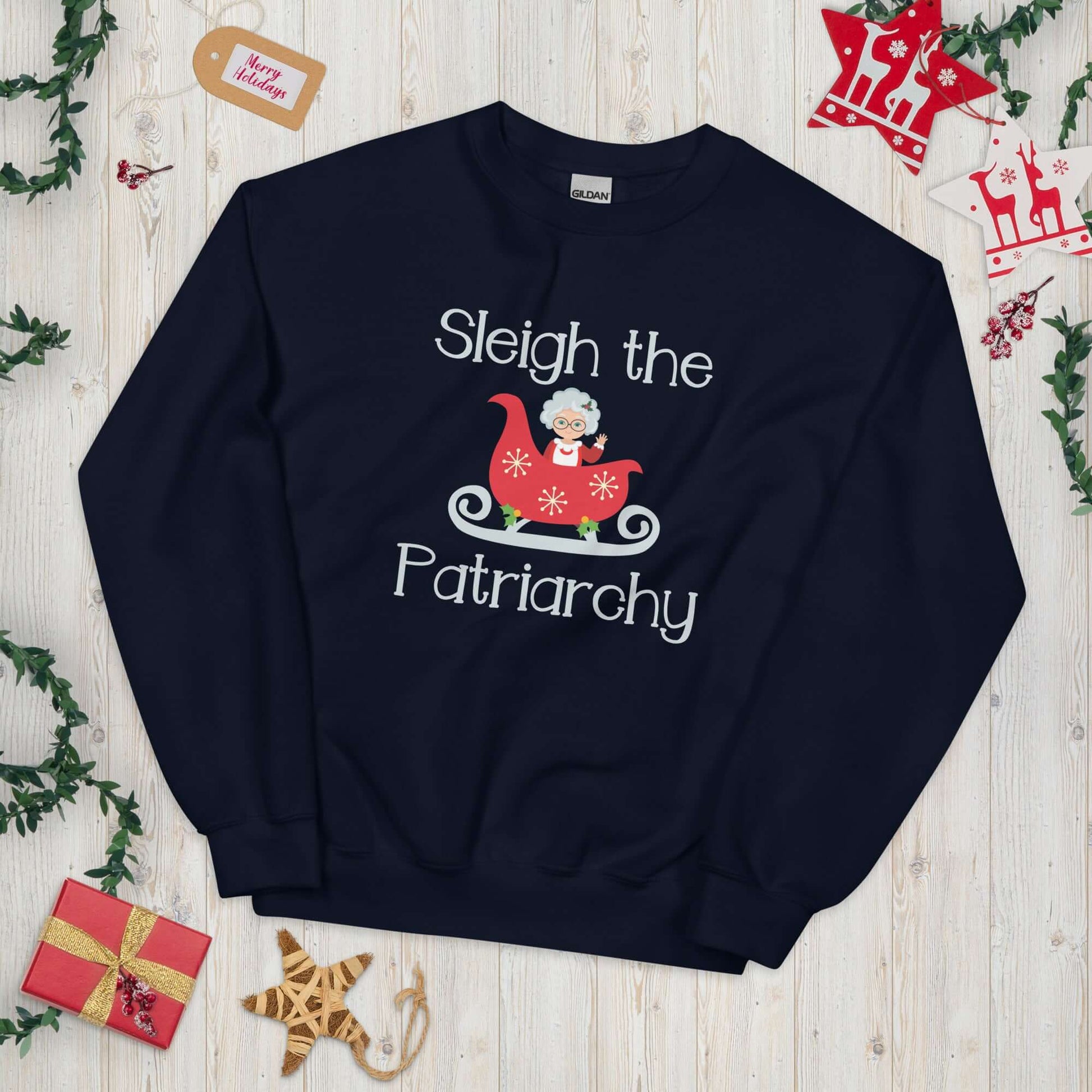 Navy blue crewneck sweatshirt with graphic of Mrs. Claus sitting in a sleigh and the words Sleigh the patriarchy printed on the front.