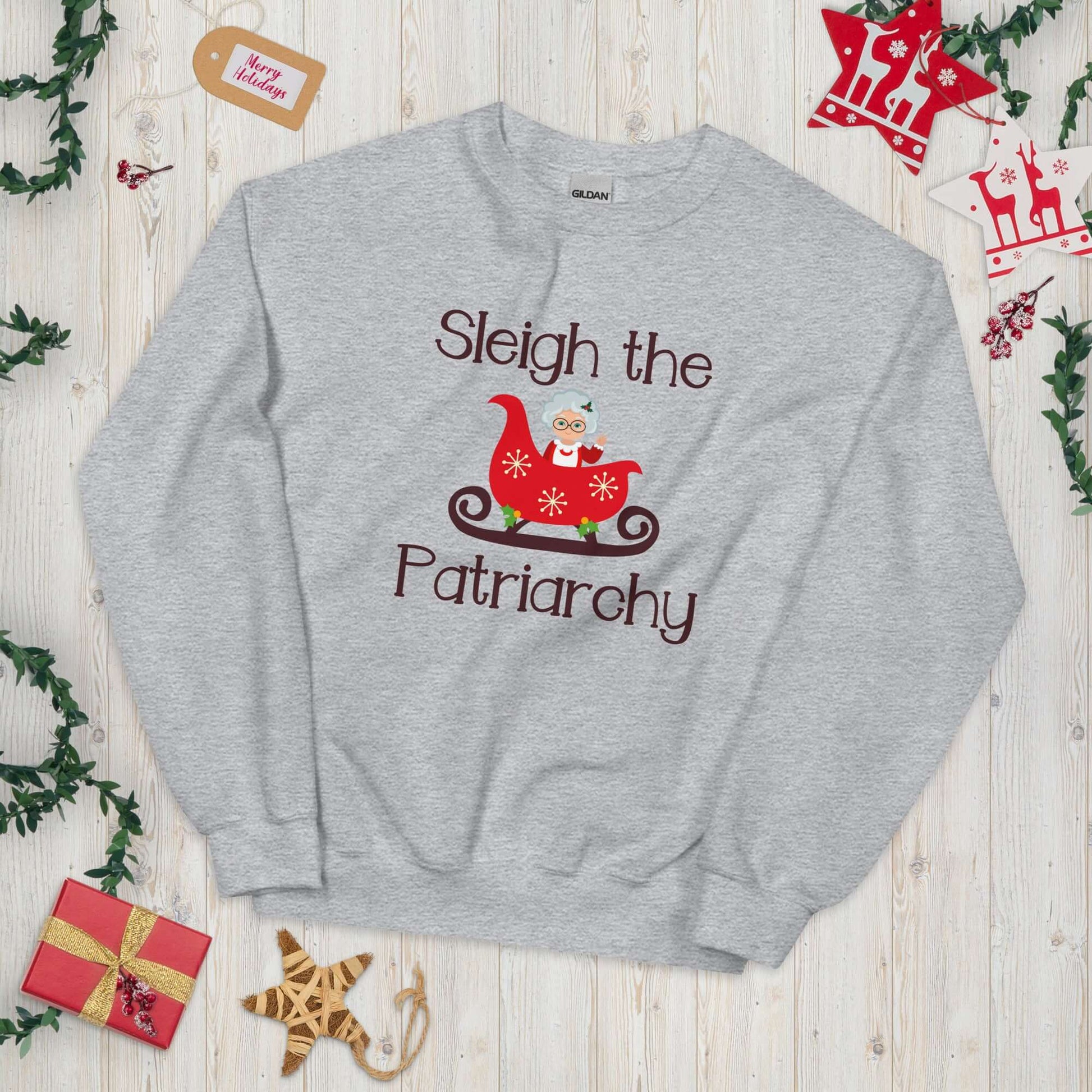 Light grey crewneck sweatshirt with graphic of Mrs. Claus sitting in a sleigh and the words Sleigh the patriarchy printed on the front.