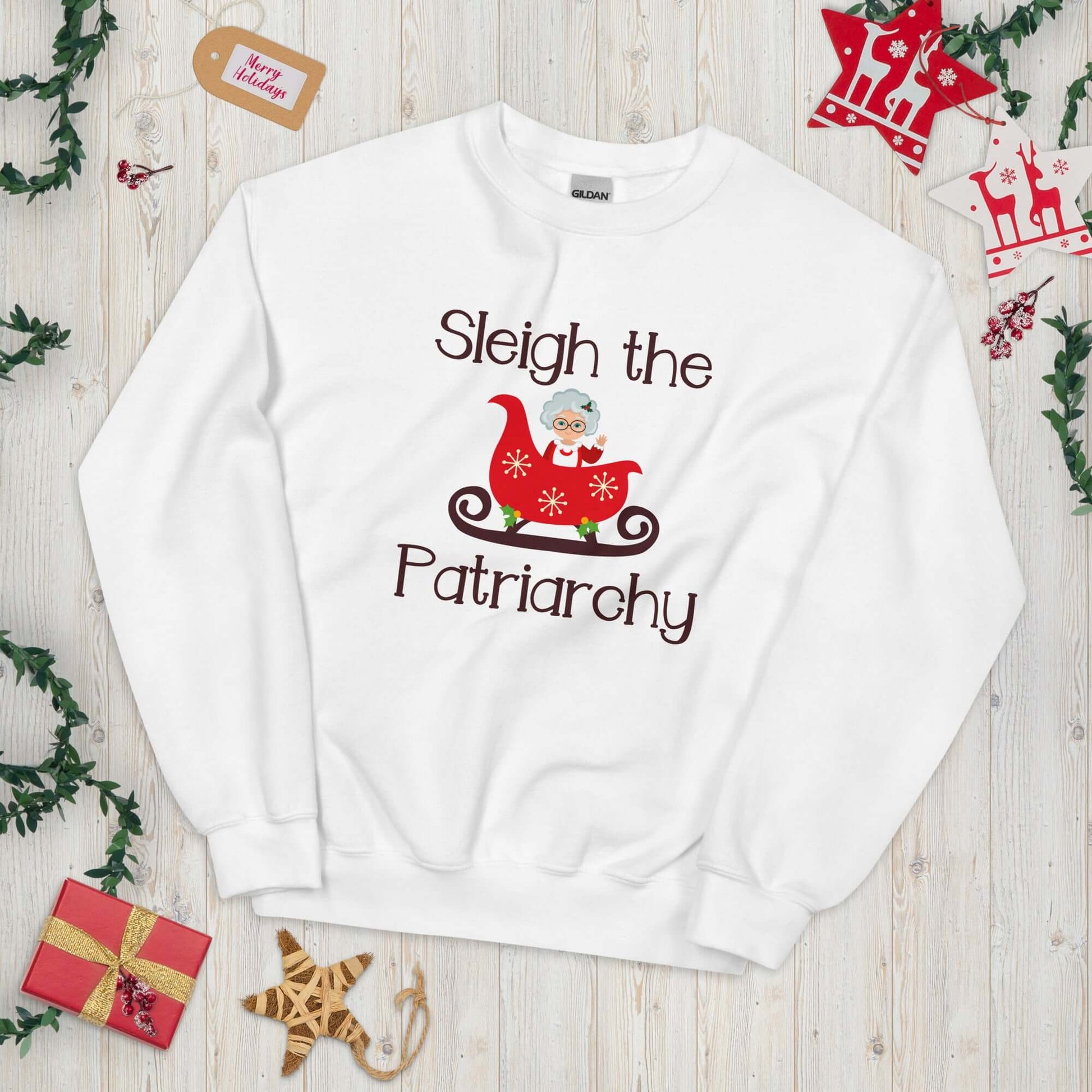 White crewneck sweatshirt with graphic of Mrs. Claus sitting in a sleigh and the words Sleigh the patriarchy printed on the front.