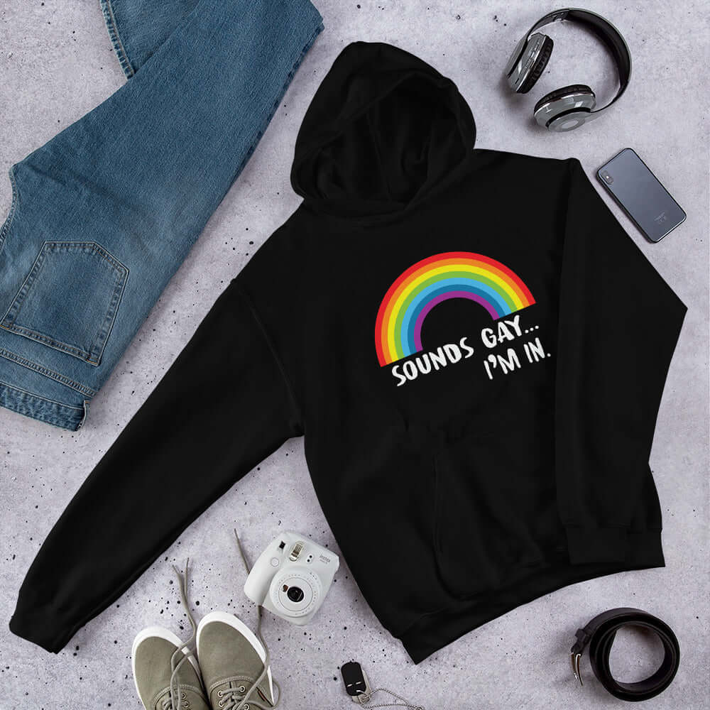 Black hoodie sweatshirt that has an image of a rainbow and the phrase Sounds gay, I'm in printed on the front