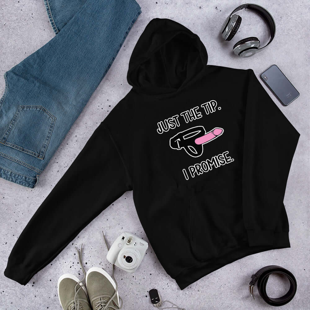 Black hoodie sweatshirt that has an image of a strap-on dildo and the words Just the tip, I promise printed on the front. The graphics are pink, black and white.