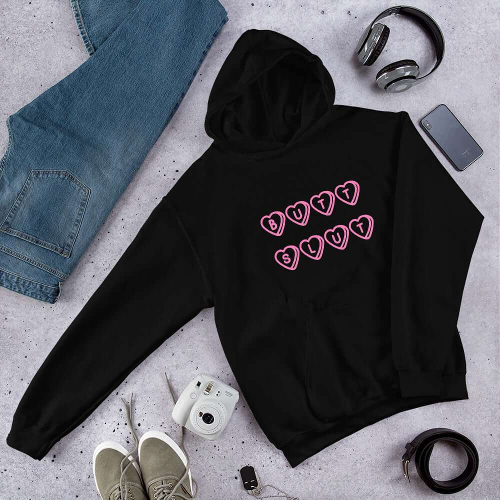 Black hoodie sweatshirt with the words Butt Slut printed in pink on the front. Pink hearts are around each letter in the text.