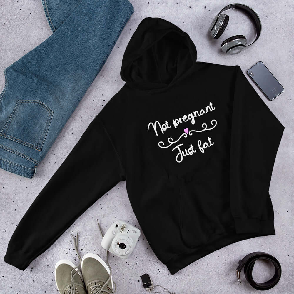 Black hoodie sweatshirt with the words Not pregnant just fat printed on the front with a heart.