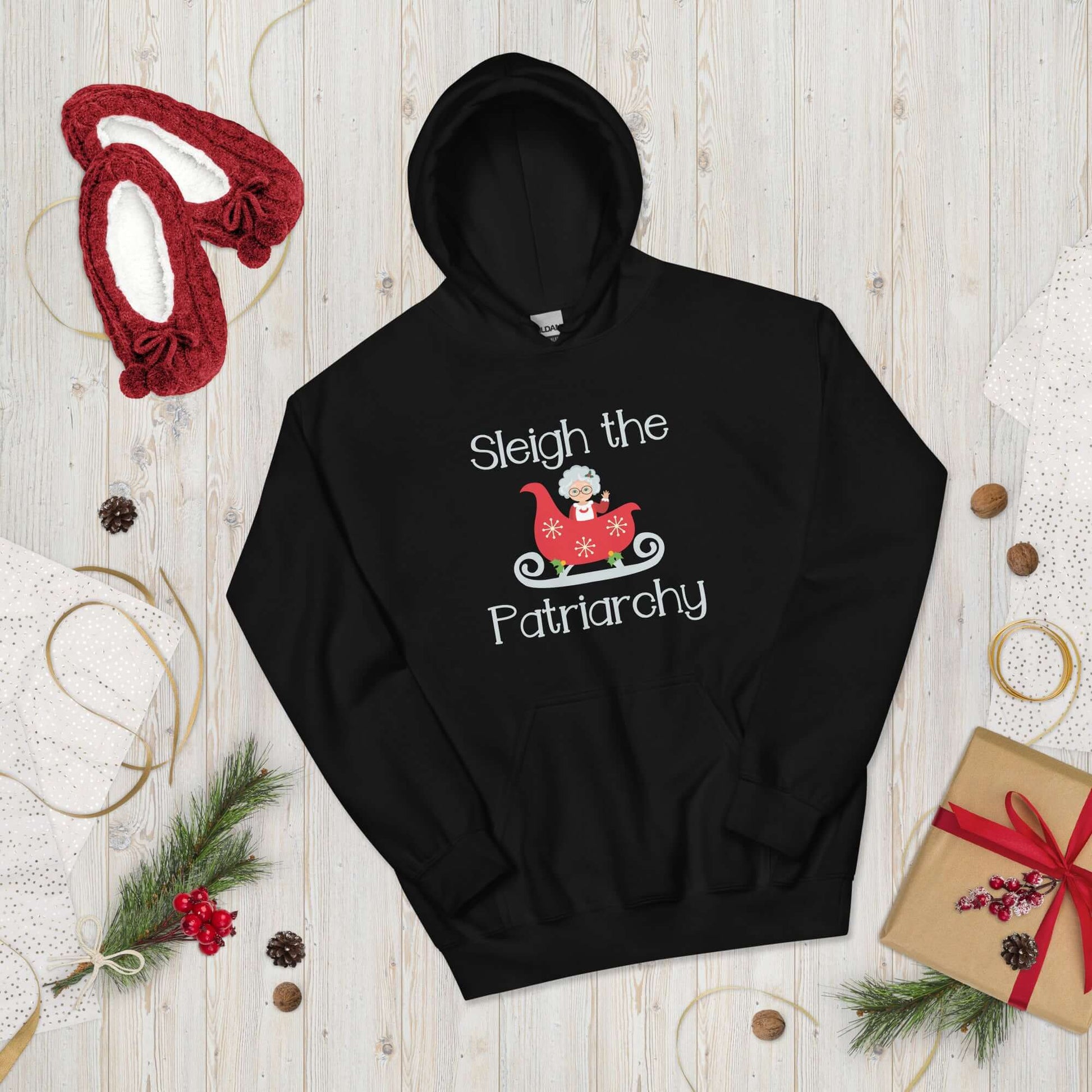 Black hooded sweatshirt with graphic of Mrs. Claus sitting in a sleigh and the words Sleigh the patriarchy printed on the front.