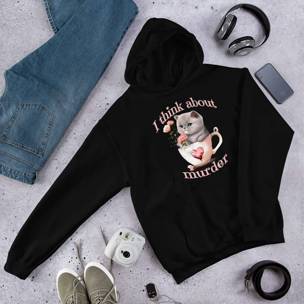 Black hooded sweatshirt that says I think about murder with image of cute fluffy kitten sitting in a teacup printed on the front.