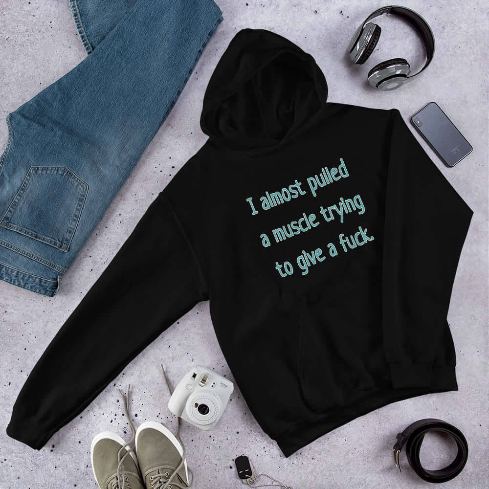 Black hooded sweatshirt with the words I Almost pulled a muscle trying to give a fuck printed on the front.