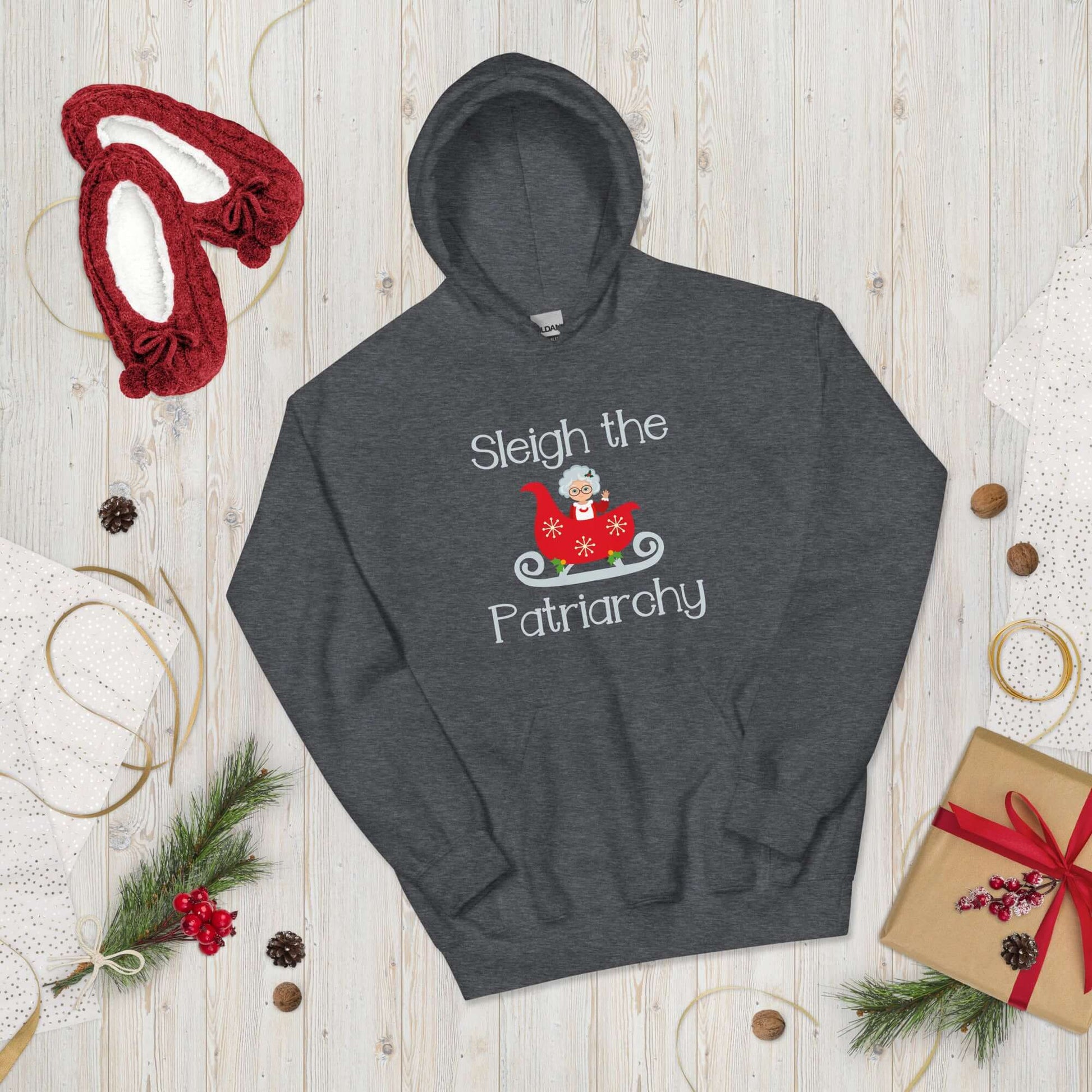 Dark grey hooded sweatshirt with graphic of Mrs. Claus sitting in a sleigh and the words Sleigh the patriarchy printed on the front.