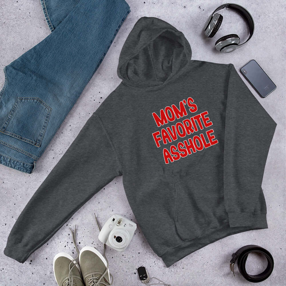 Dark grey hooded sweatshirt with the words Mom's favorite asshole printed in red on the front. 