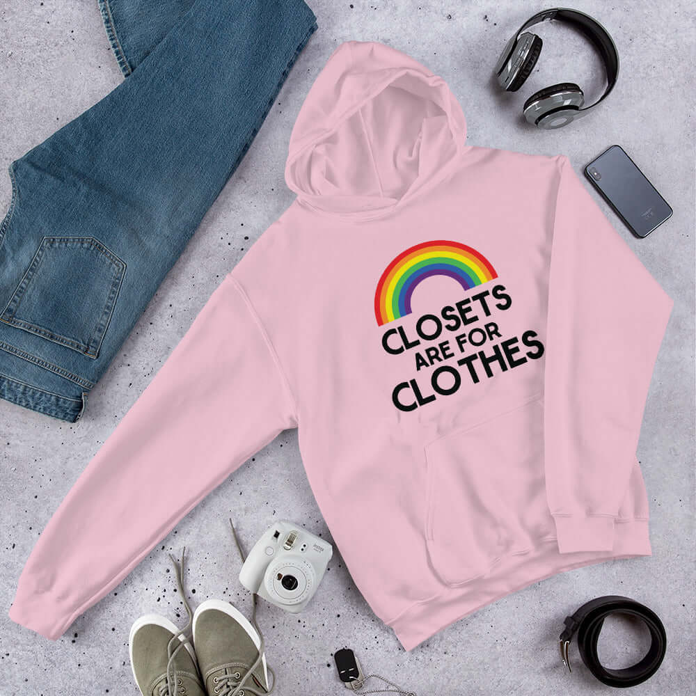 Light pink hoodie sweatshirt with a rainbow and the words Clothes are for closets printed on the front.