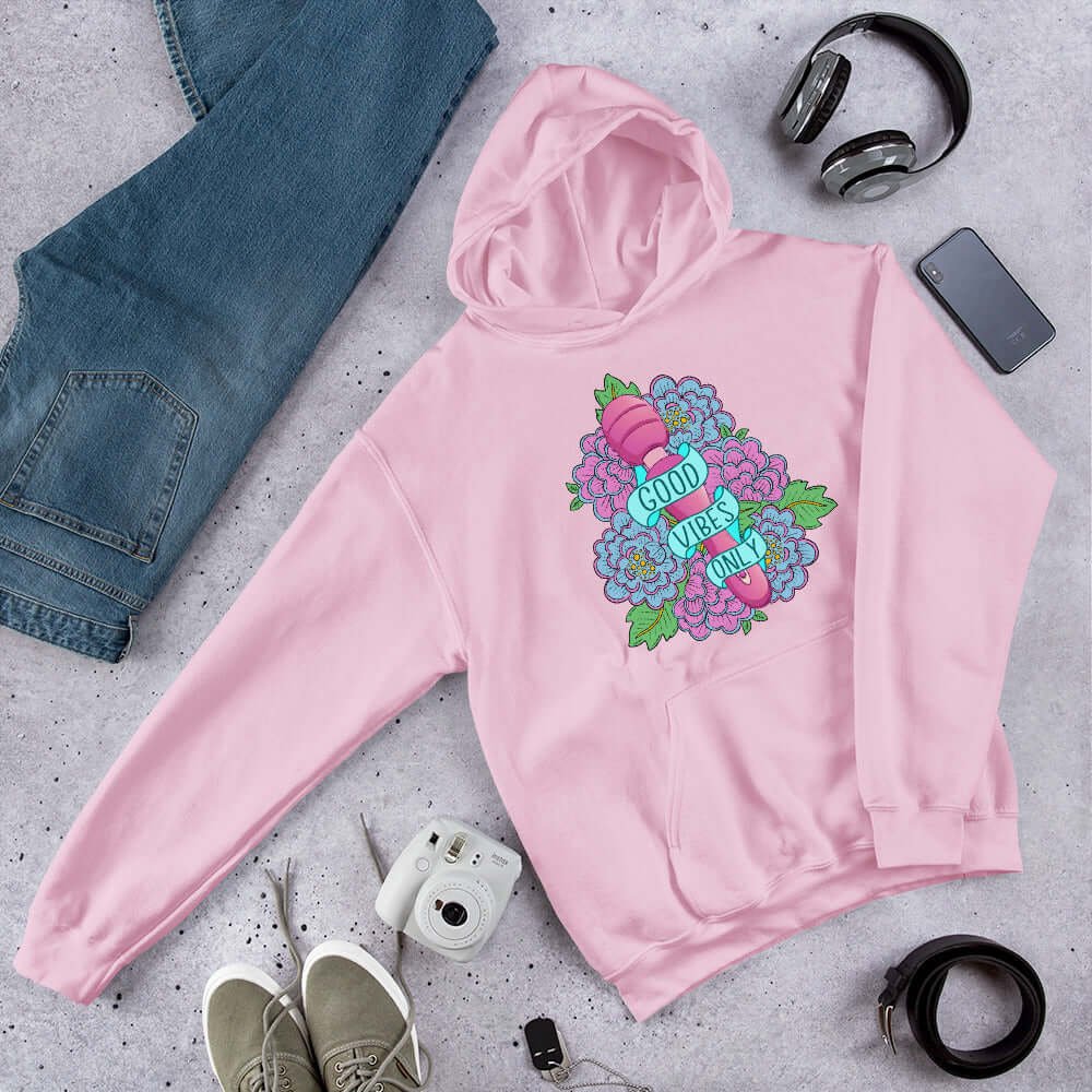 Light pink hoodie sweatshirt with graphic design that has the words Good vibes only layered over a pink wand vibrator with flowers around. The graphic design is printed on the front of the hoodie.
