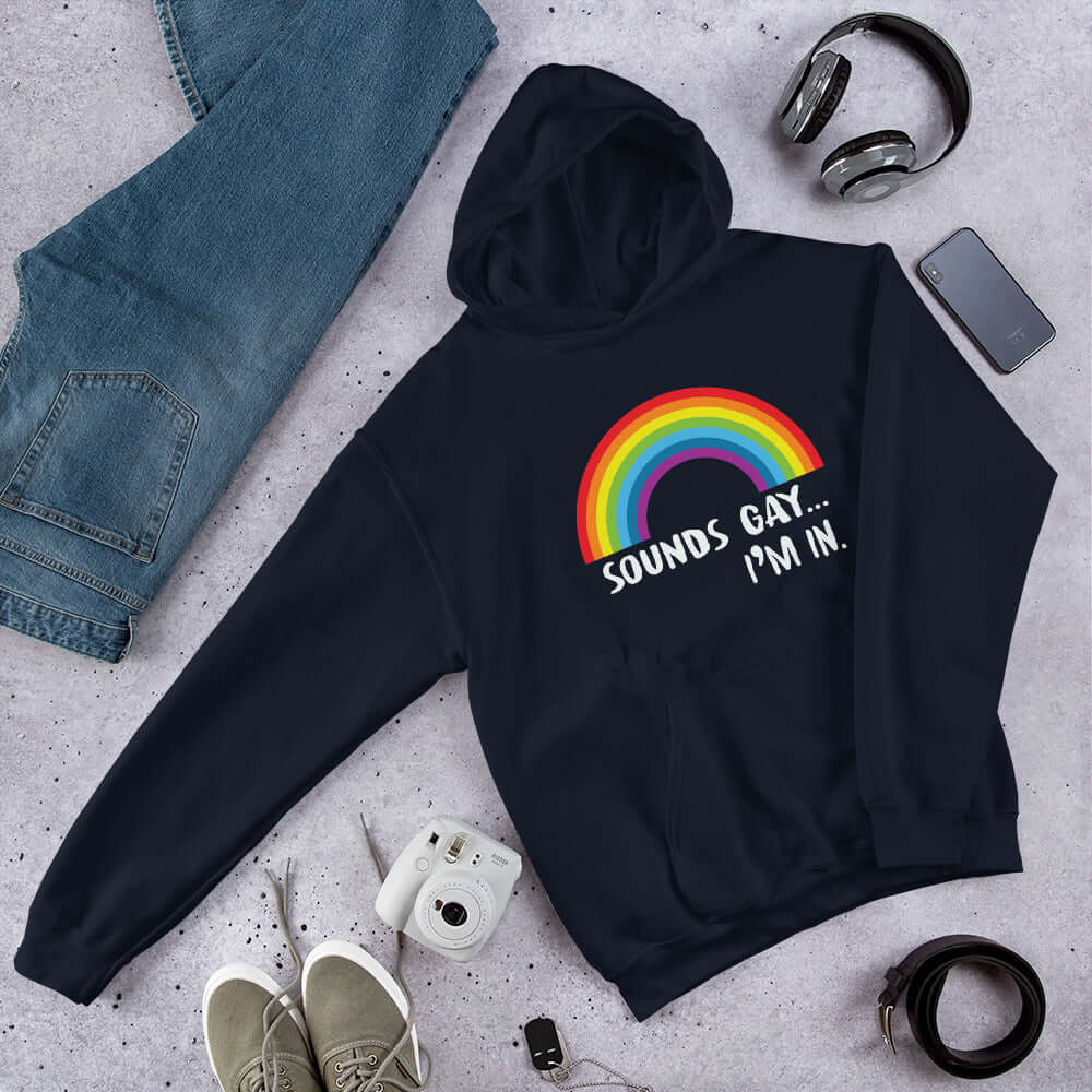 Navy blue hoodie sweatshirt that has an image of a rainbow and the phrase Sounds gay, I'm in printed on the front