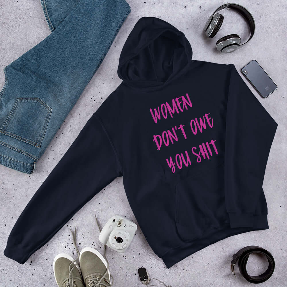 Navy blue hoodie sweatshirt with the words Women don't owe you shit printed on the front in pink.