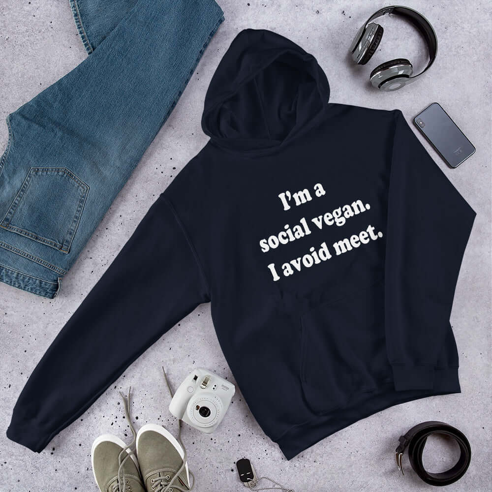 Navy blue hoodie sweatshirt with the pun phrase I'm a social vegan, I avoid meet printed on the front.