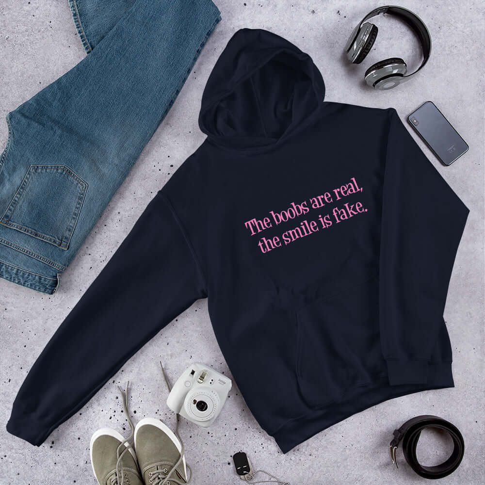 Navy blue hoodie sweatshirt with the phrase The boobs are real, the smile is fake printed in pink on the front.