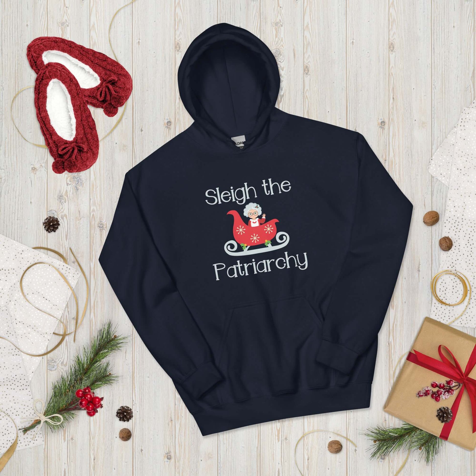 Navy blue hooded sweatshirt with graphic of Mrs. Claus sitting in a sleigh and the words Sleigh the patriarchy printed on the front.