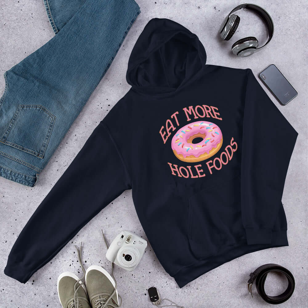 Navy blue hoodie sweatshirt with an image of a donut with pink icing and sprinkles and the words Eat more hole foods printed on the front.