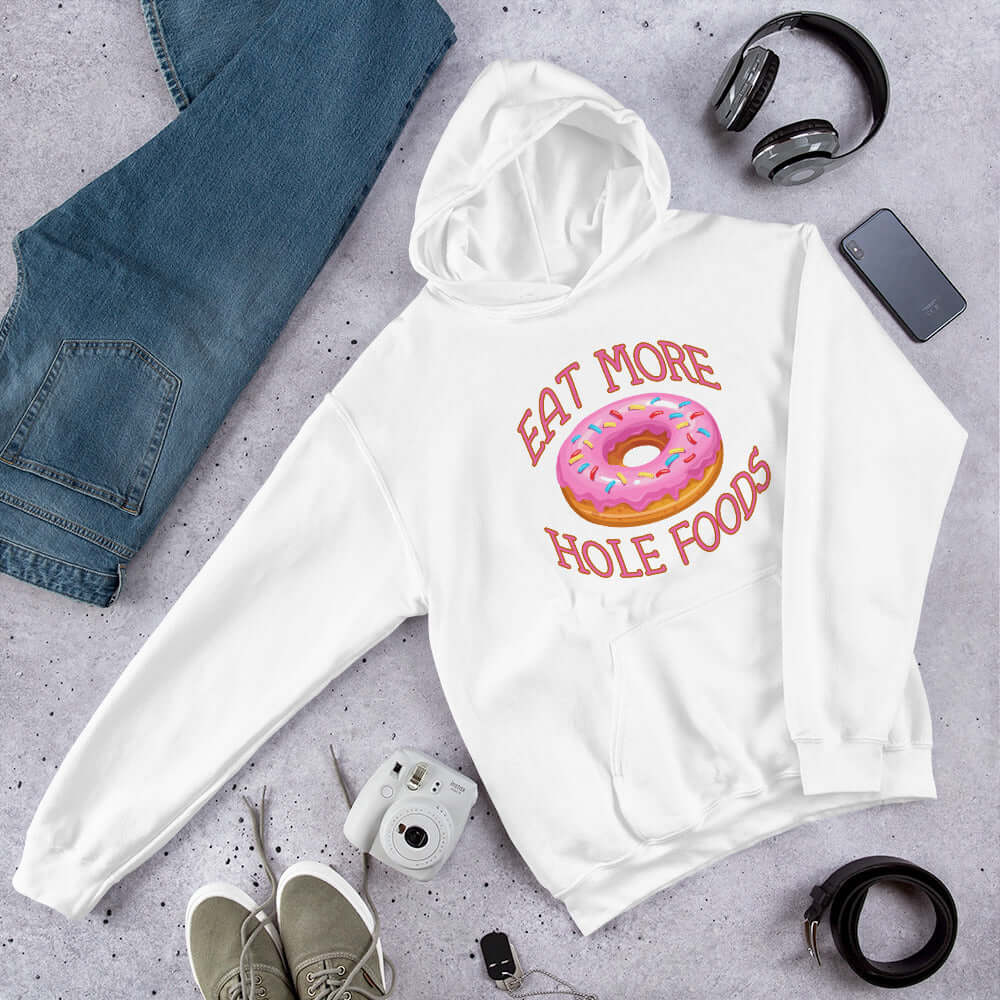 White hoodie sweatshirt with an image of a donut with pink icing and sprinkles and the words Eat more hole foods printed on the front.