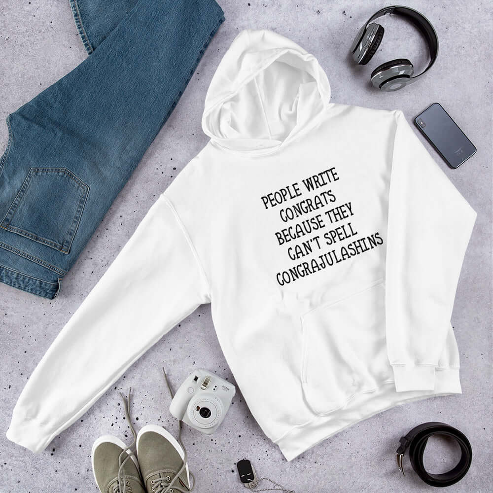 White hooded sweatshirt with the words People write congrats because they can't spell congratulations printed on the front. The word congratulations is intentionally misspelled.