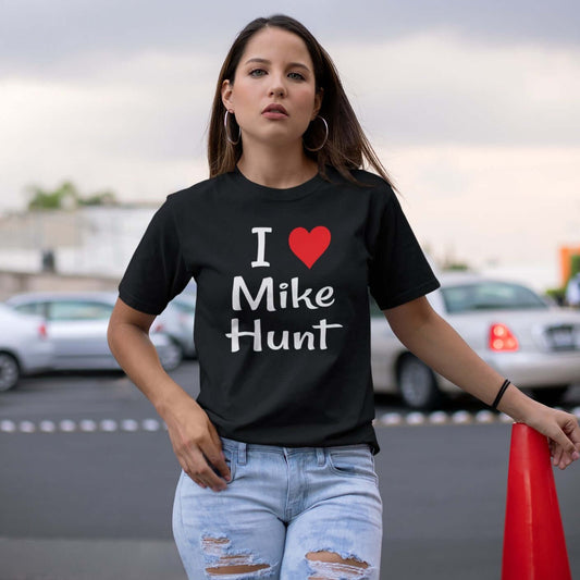 Woman wearing a black t-shirt with pun I heart Mike Hunt printed on the front. The heart is red.