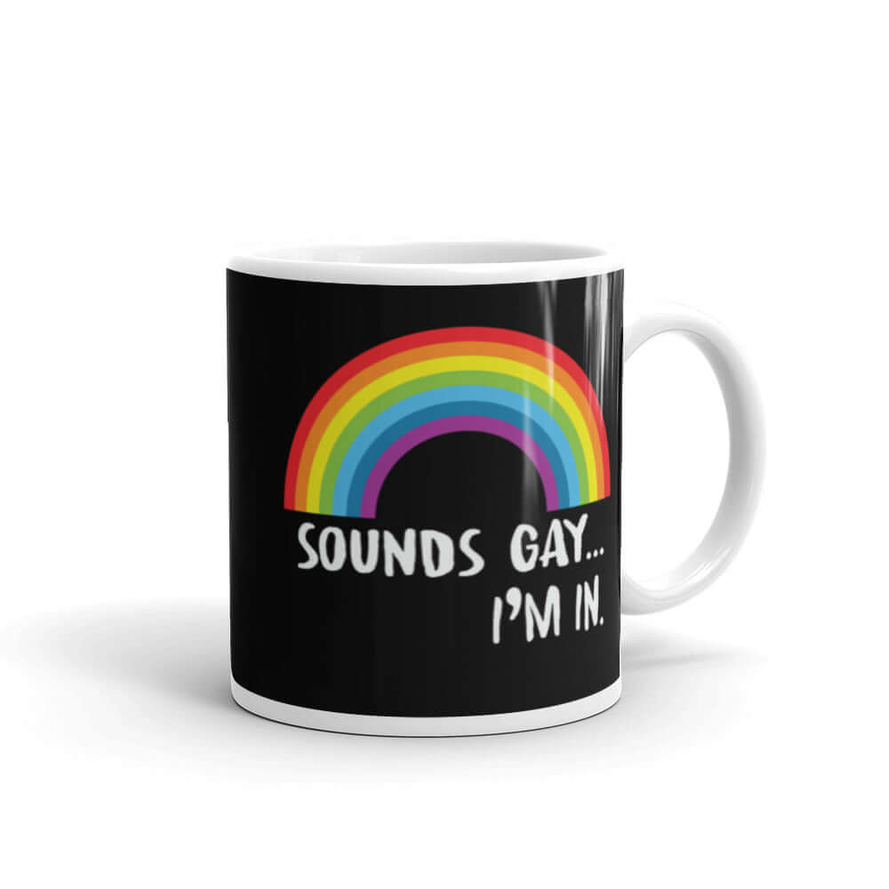 Black and white ceramic coffee mug that has an image of a rainbow and the phrase Sounds gay, I'm in printed on both sides.