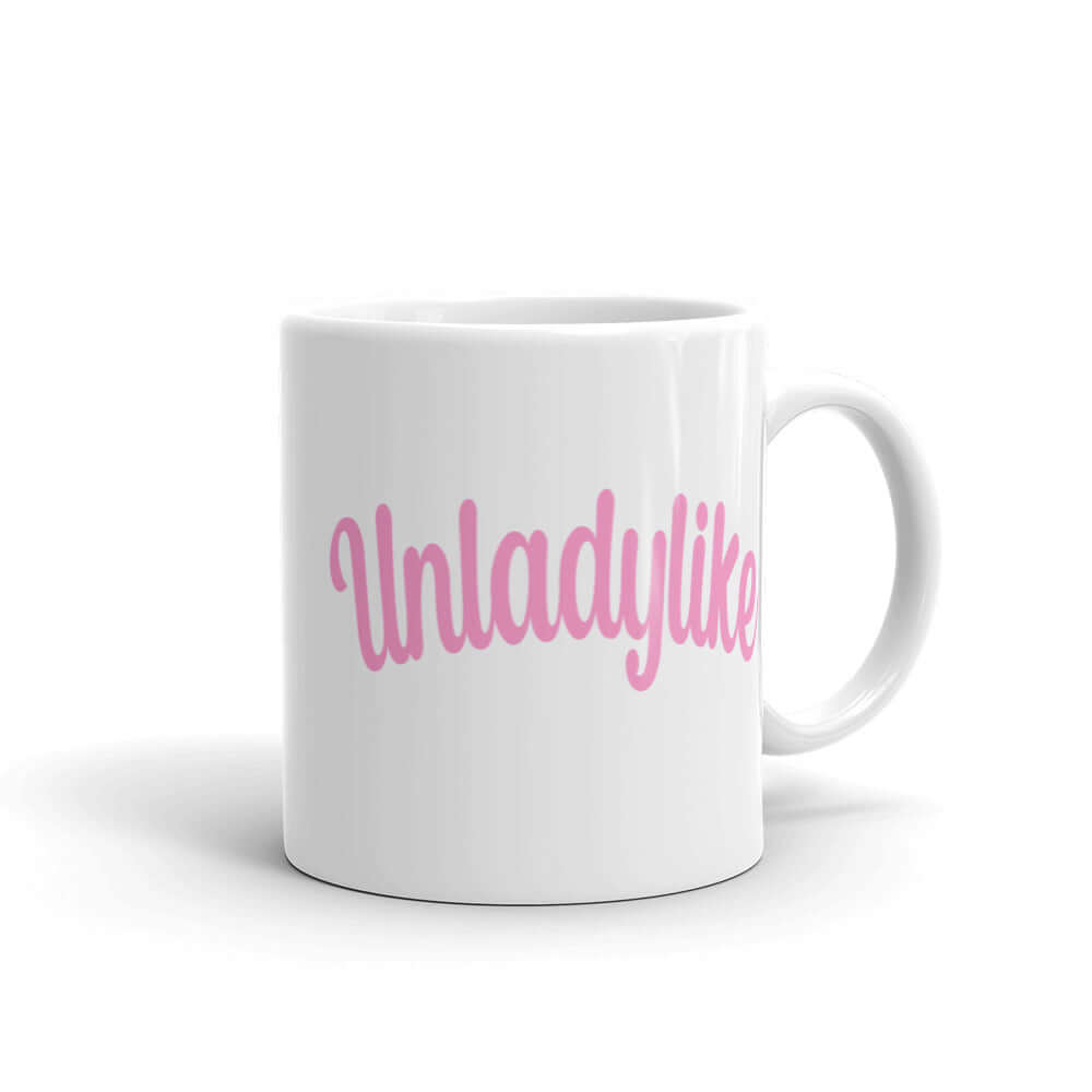 White ceramic coffee mug with the word Unladylike printed in pink on both sides.