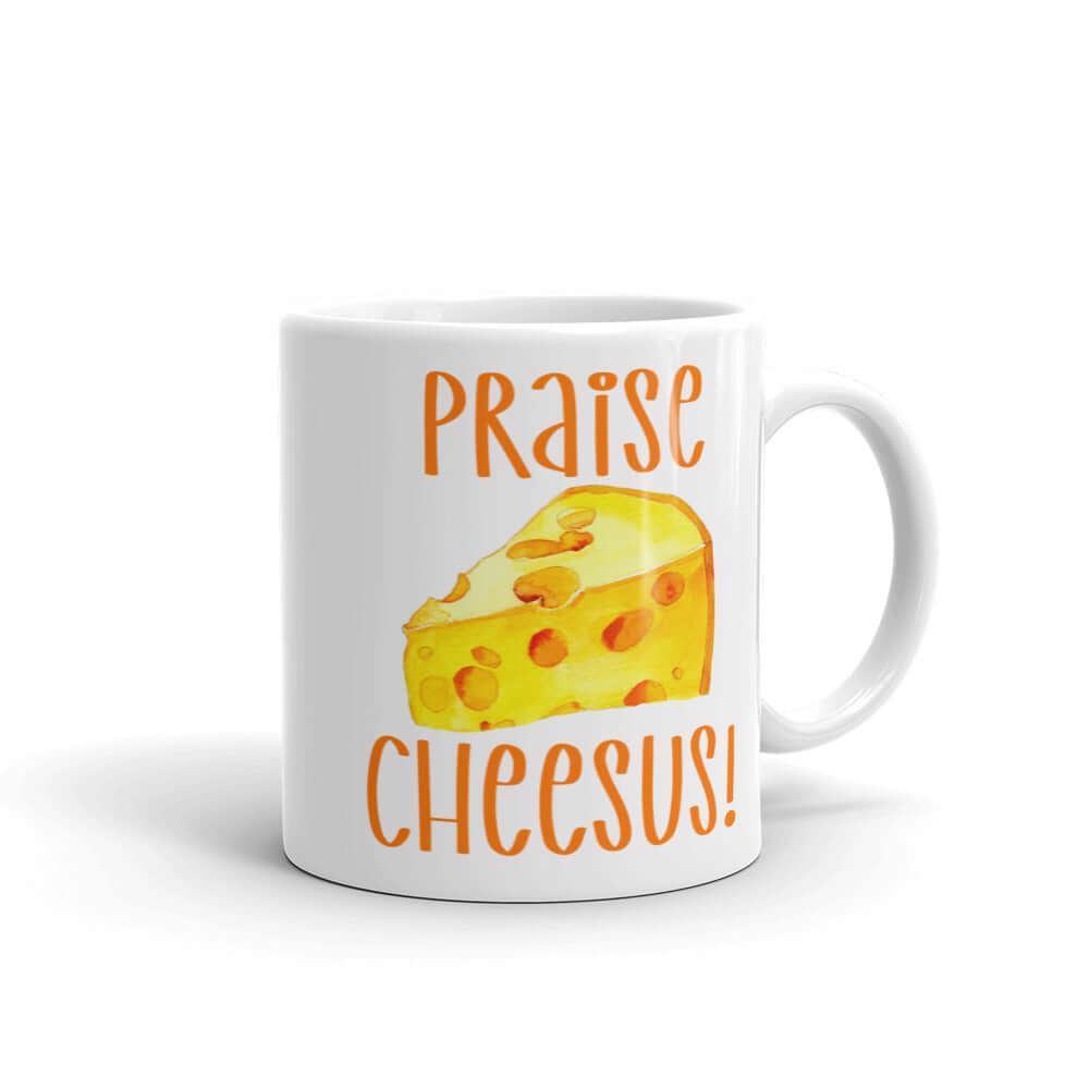 White ceramic coffee mug with funny graphics of a piece of swiss cheese and the words Praise Cheesus printed on both sides of the mug in yellow and orange.