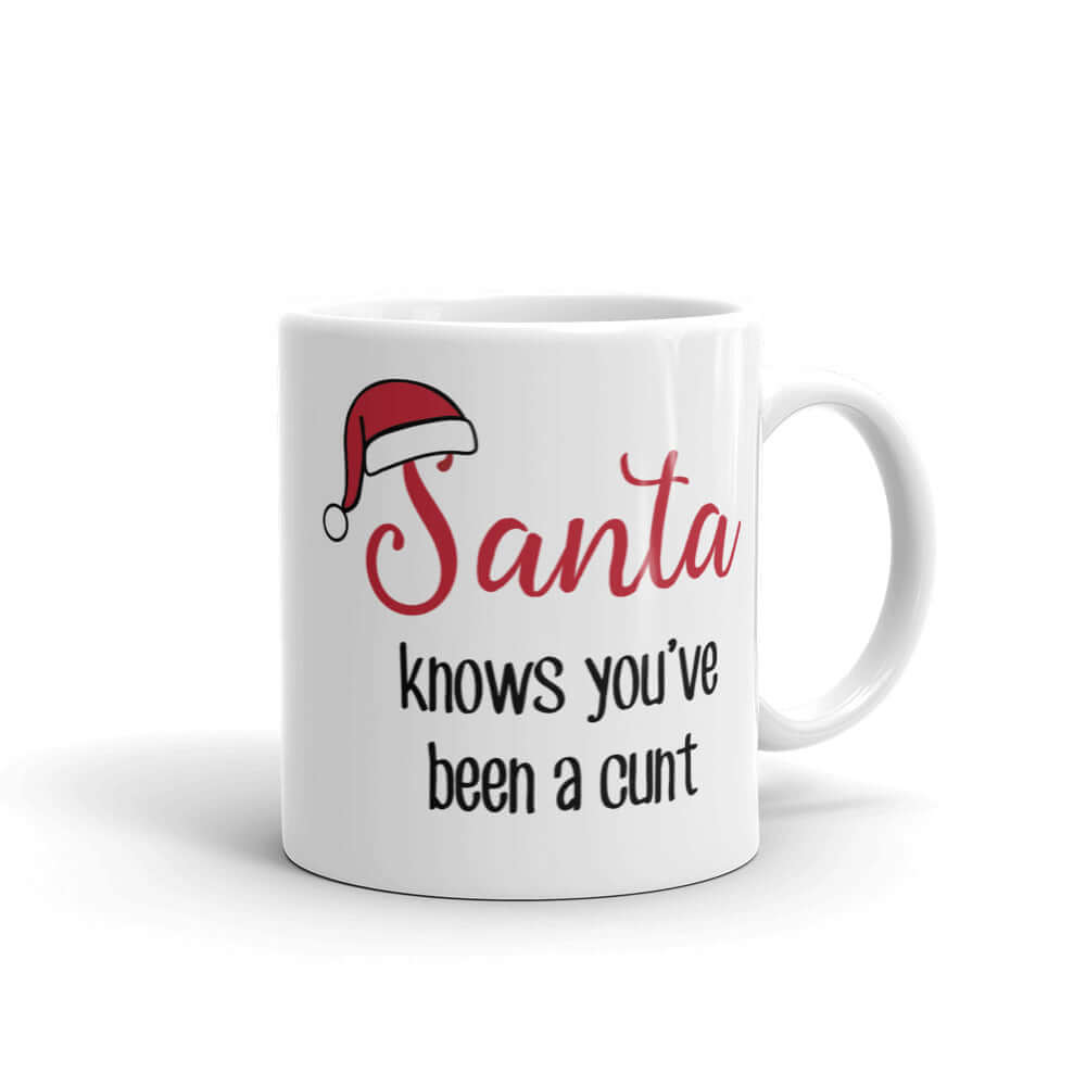 White ceramic mug with the words Santa knows you've been a cunt printed on both sides. There is a red Santa hat on the S in Santa.