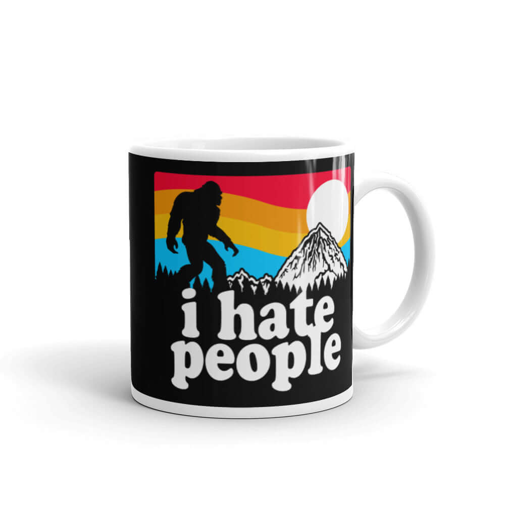 White coffee mug with graphic of Bigfoot walking into the sunset with the words I hate people printed on both sides. 