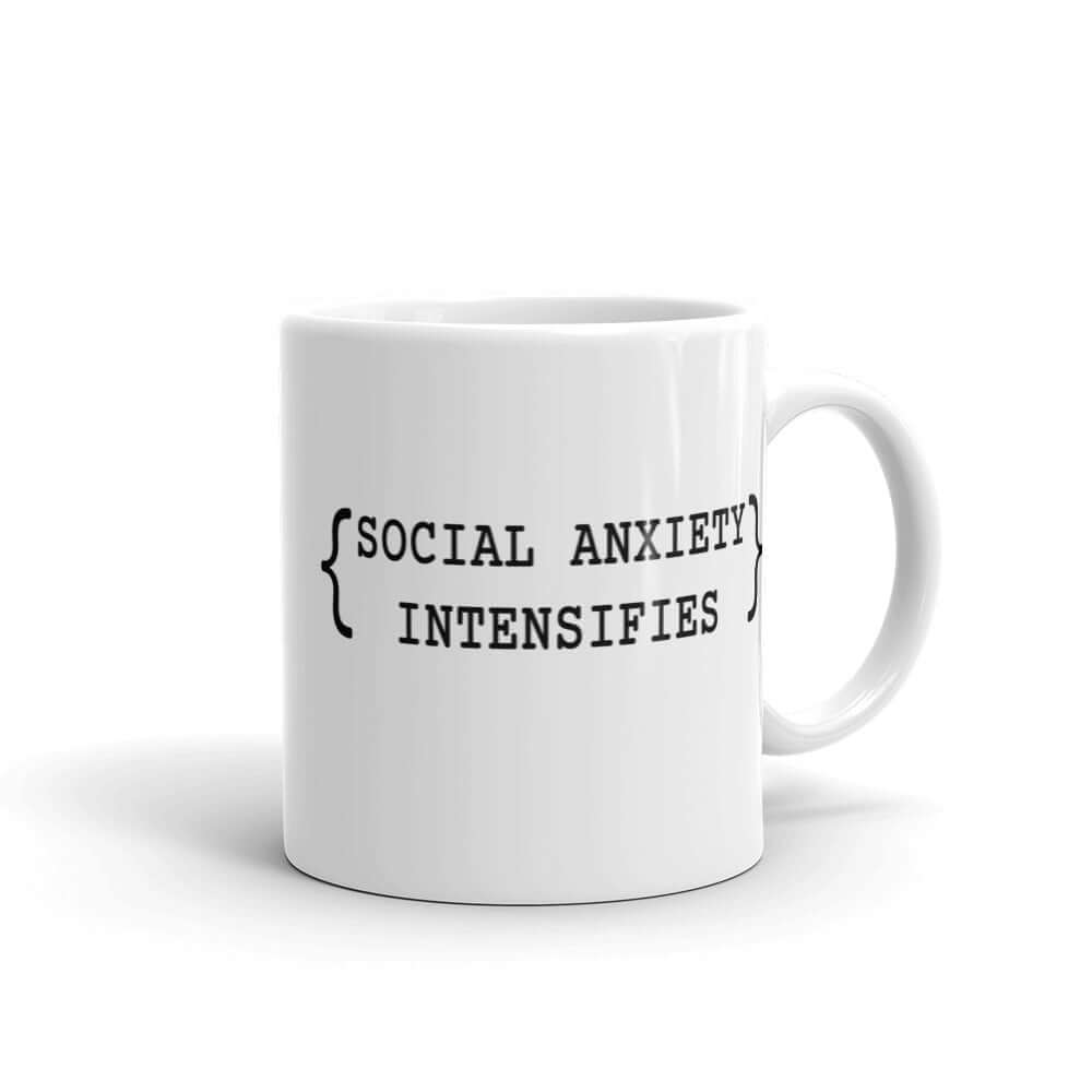 White ceramic coffee mug with the words Social anxiety intensifies printed on both sides.