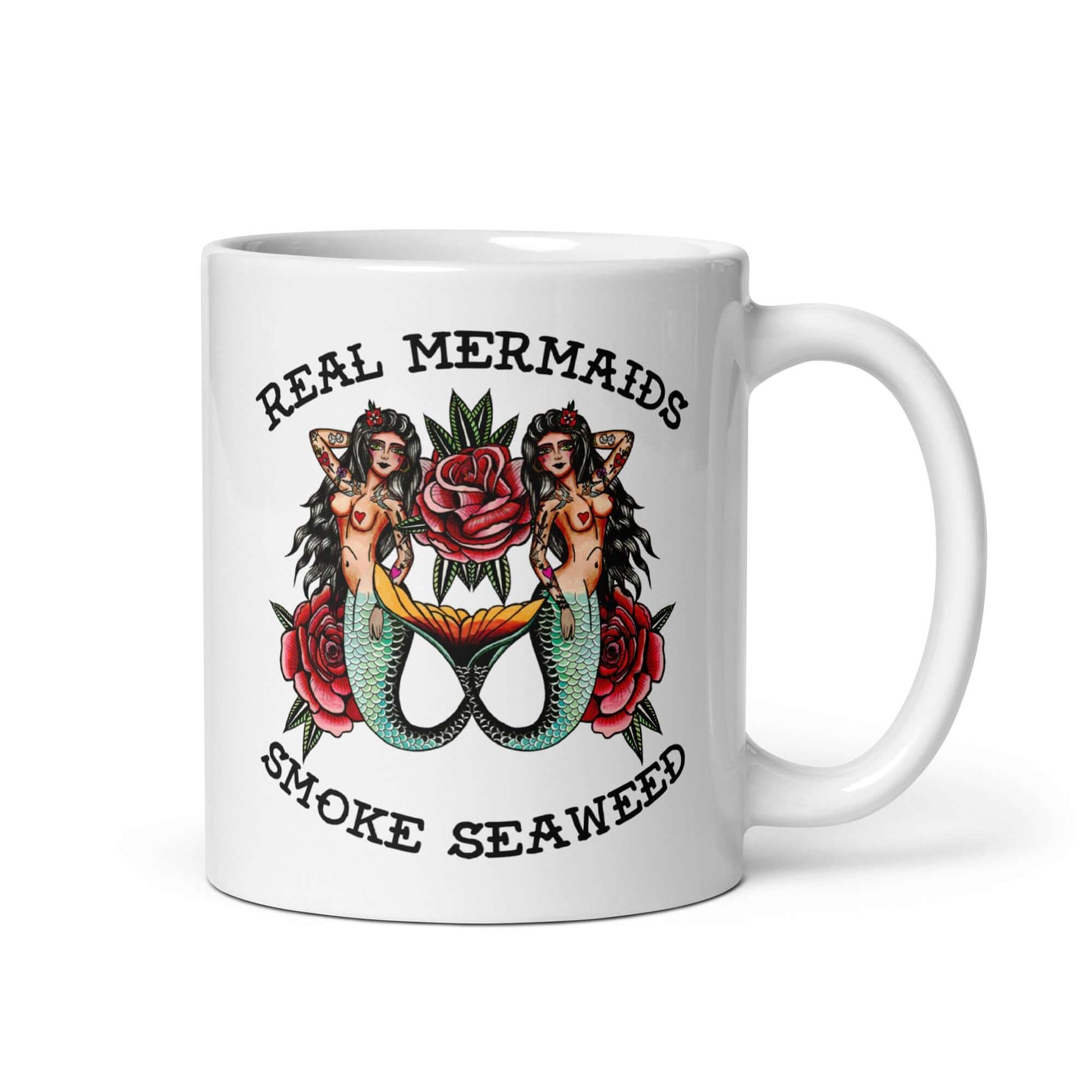 White ceramic mug with image of 2 mermaids and the words Real mermaids smoke seaweed printed on both sides.