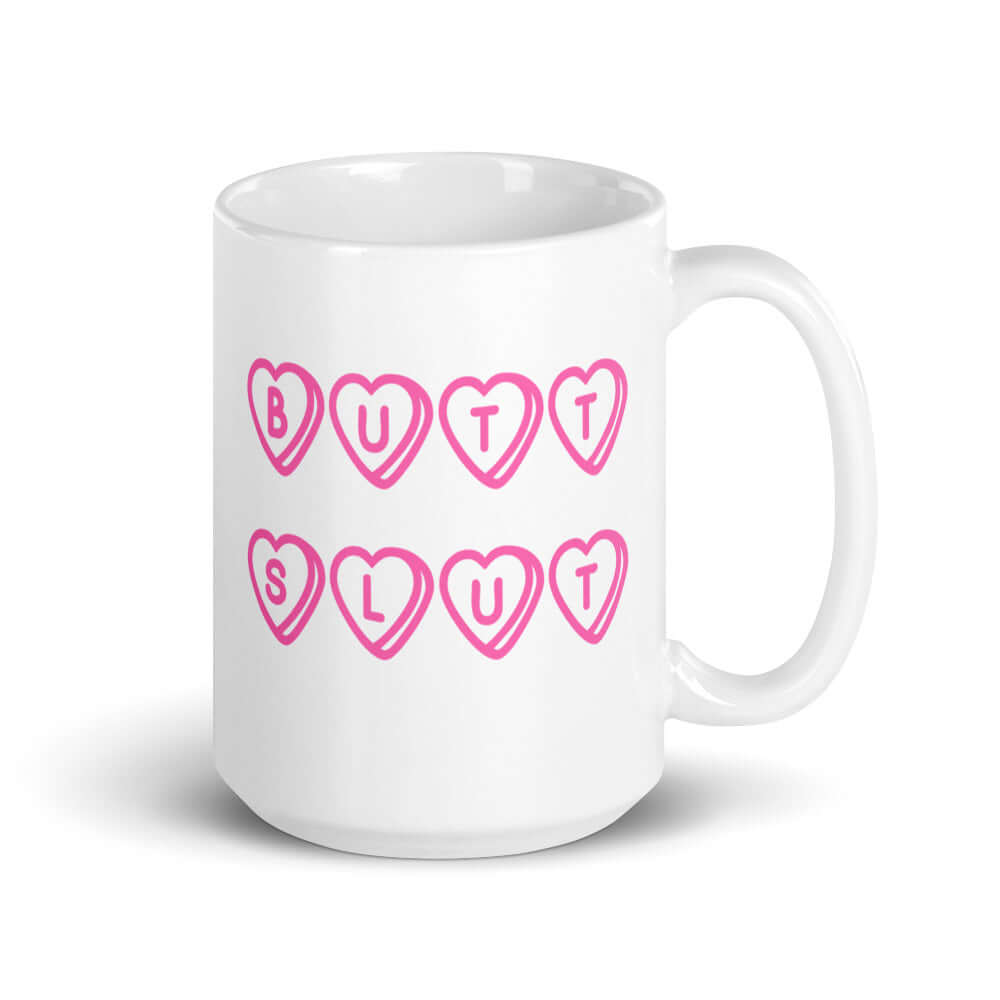 White ceramic mug with the words Butt Slut printed in pink on both sides. Pink hearts are around each letter in the text.