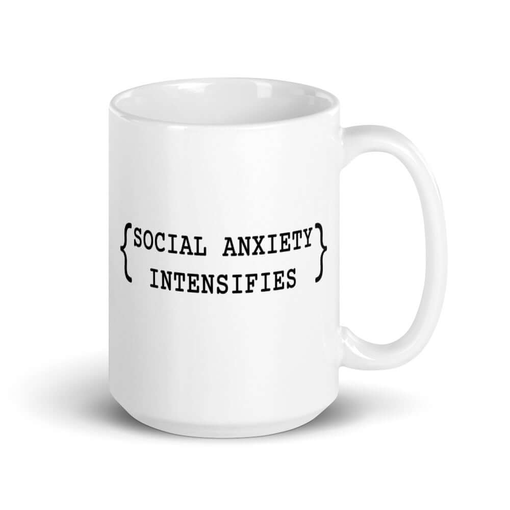 White ceramic coffee mug with the words Social anxiety intensifies printed on both sides.