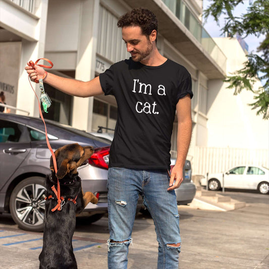 Man walking a dog wearing a black t-shirt with the words I'm a cat printed on the front.