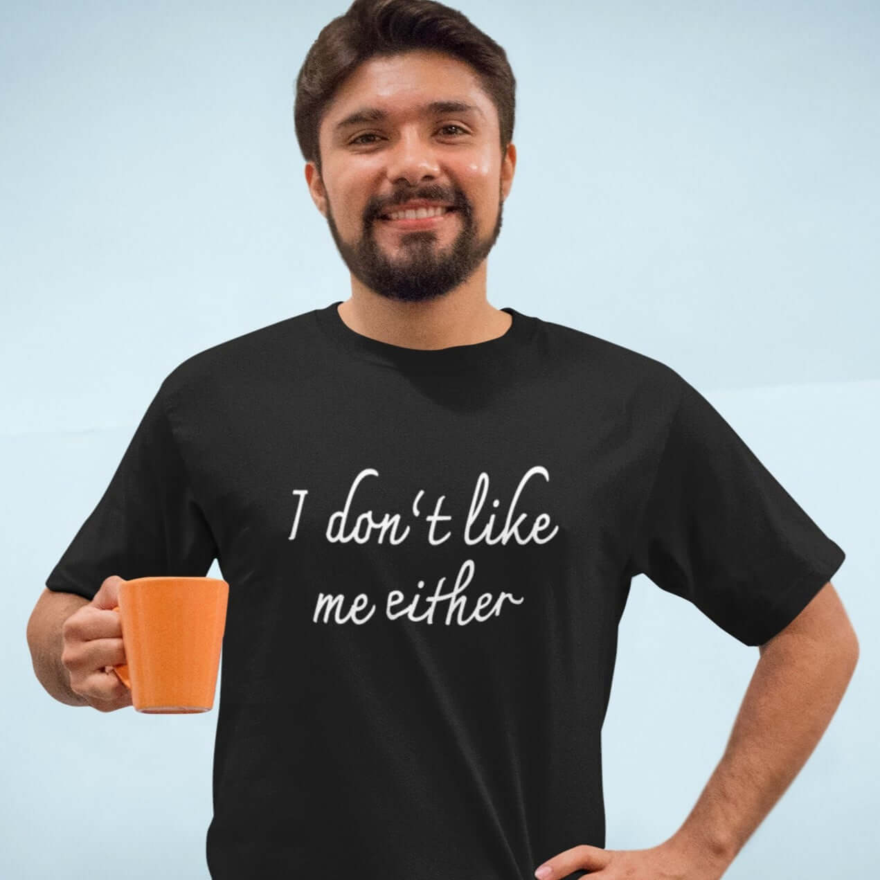 Man holding cup of coffee wearing a black t-shirt with the words I don't like me either printed on the front.