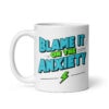 White ceramic mug with the phrase 'Blame is on the anxiety' printed on both sides of the mug. The graphics are bold and in aqua and lime green.