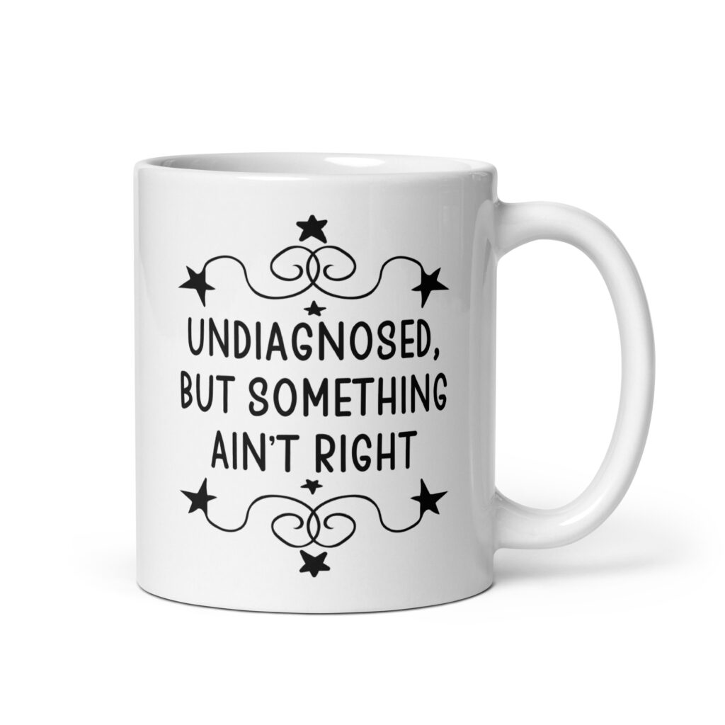 White ceramic mug with the text 'Undiagnosed, but something ain't right' printed on both sides.