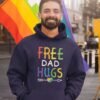 Man at pride event wearing a navy blue hoodie sweatshirt with the text 'Free Dad hugs' printed on the front in rainbow letters.