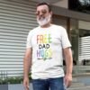 Older bearded man wearing a white t-shirt with the text 'Free Dad hugs' printed on the front in rainbow letters.