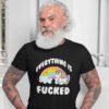 Tattooed older man with a beard wearing a black t-shirt with a graphic of a kawaii style unicorn and a pastel rainbow with the text 'Everything is fucked' printed on the front.
