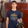 Man holding a cat while wearing a navy blue t-shirt. The shirt has images of mushrooms and the text 'If mushrooms can grow from shit, so can you.' printed on the front.