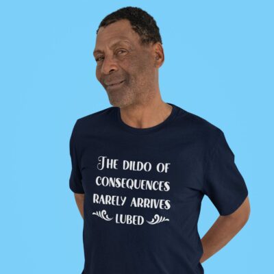 Man wearing a navy blue t-shirt with the text 'The dildo of consequences rarely arrives lubed' printed on the front.