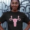 Woman wearing black t-shirt with image of a pink uterus flipping middle finger graphic printed on the front.
