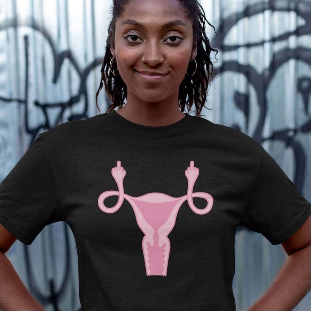 Woman wearing black t-shirt with image of a pink uterus flipping middle finger graphic printed on the front.