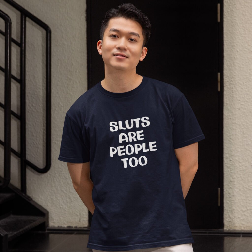 Man wearing a navy blue t-shirt with the text 'Sluts are people too' printed on the front.