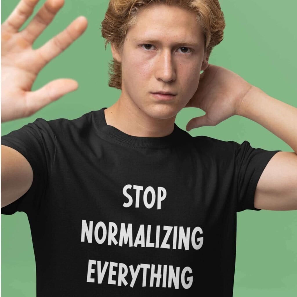 Man wearing a black t-shirt with the text 'Stop normalizing everything' printed on the front.