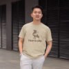 Man wearing a sand color t-shirt with an image of a pigeon and the words 'That's coo.' printed on the front.