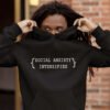 Man hiding his face in a hoodie sweatshirt. The hoodie has the text 'Social anxiety intensifies' printed on the front.